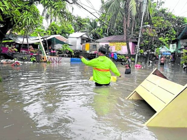 A man wades through thigh-high flood waters in Barangay Labangon, Cebu City