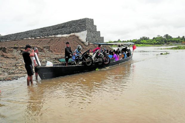 Villagers ride a banca to cross the Alicaocao bridge in Cauayan City
