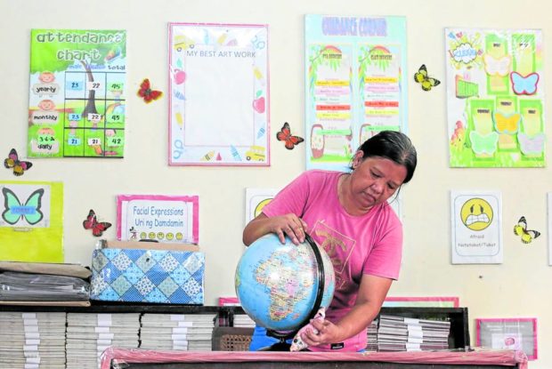 A woman dusting off a globe in a classroom. STORY: Teachers’ union wants current P5,000 allowance doubled