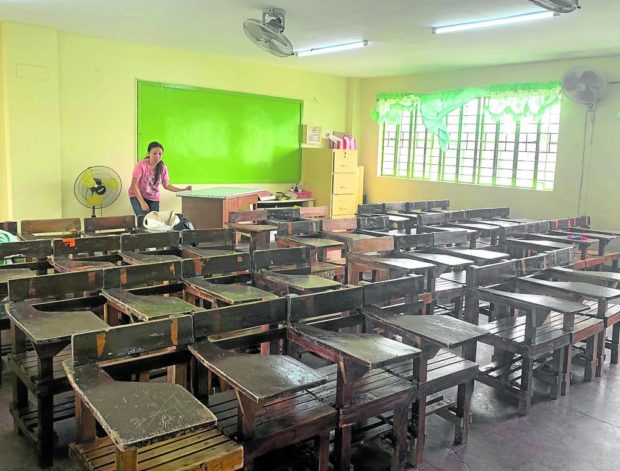 Public school teacher Julieta Golez rearranges the chairs in her classroom. FOR STORY: Teachers seek clear-cut policy on working hours