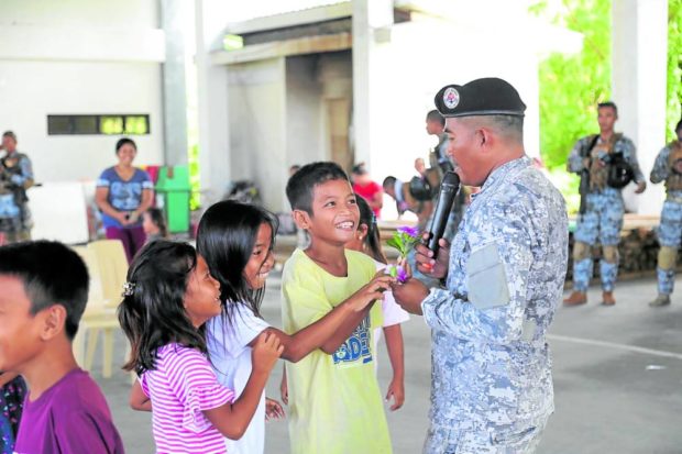 MOLDING MINDS School-aged chidren approach a coast guardsman during a program in Pag-asa Island. —PHOTO courtesy of philippiine coast guard