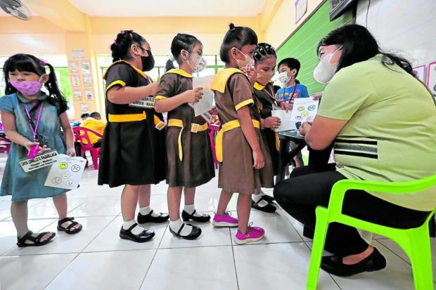 SEAT WORK CHECK Kindergarten pupils queue to have their seat work checked by their teacher at San Diego Elementary School in Quezon City during the first day of classes on Monday. —GRIG C. MONTEGRANDE