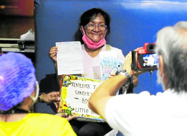 A resident of San Juan City poses for the camera with the money she received from the government in this 2020 photo. The cash assistance was meant to help poor families cope with the impact of the pandemic. STORY: No more COVID-related ‘ayuda’ in 2023 budget