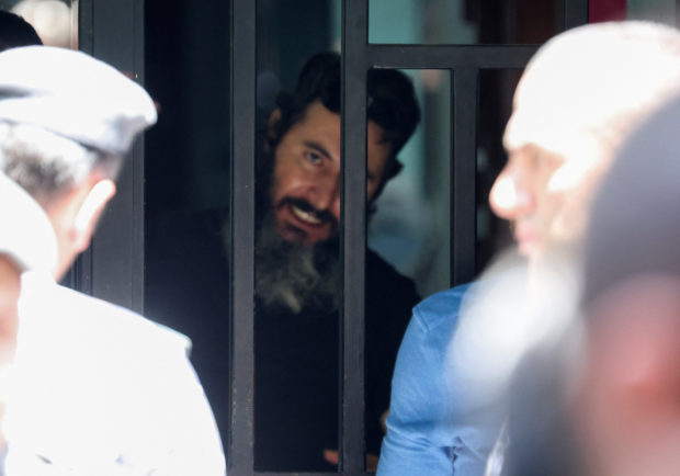 A man who security sources said is armed and holding hostages while demanding the return of his bank deposits, is seen through the door of the Federal Bank of Lebanon in Hamra, Lebanon, August 11, 2022. REUTERS/Mohamed Azakir