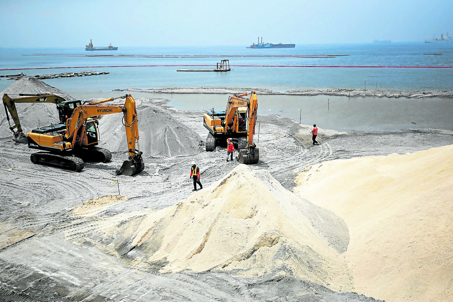 In this September 3, 2020, photo, workers prepare ground dolomite to create a white sand appearance for a portion of Manila Bay