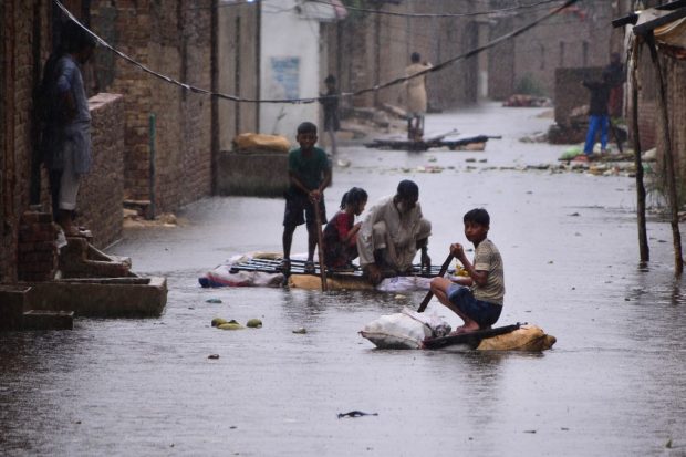 Residents use rafts to make their way along a waterlogged street in a residential area after a heavy monsoon rainfall in Hyderabad on August 24, 2022.