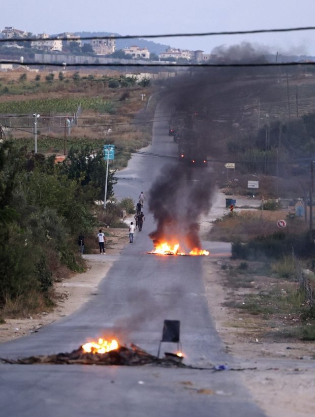 Palestinian protesters burn tires on a road as members of the Israeli army deploy to demolish houses in in Rummanah town in the occupied West Bank, on August 8, 2022.