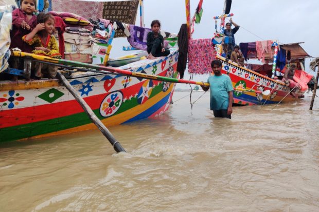 People take shelter on their boats after the Sindh River water levels rose following monsoon rainfalls in Sukkur, in Sindh province on August 24, 2022.