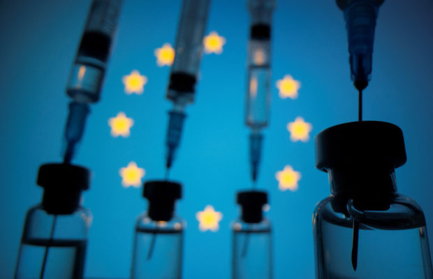 Vials and syringes are seen in front of displayed EU flag in this illustration photo taken March 16, 2021. REUTERS/Dado Ruvic/Illustration/Files