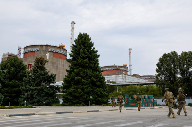 FILE PHOTO: Service members walk near the Russian-controlled Zaporizhzhia Nuclear Power Plant before the arrival of the International Atomic Energy Agency (IAEA) expert mission in the course of Ukraine-Russia conflict outside Enerhodar in the Zaporizhzhia region, Ukraine, September 1, 2022. REUTERS/Alexander Ermochenko/File Photo
