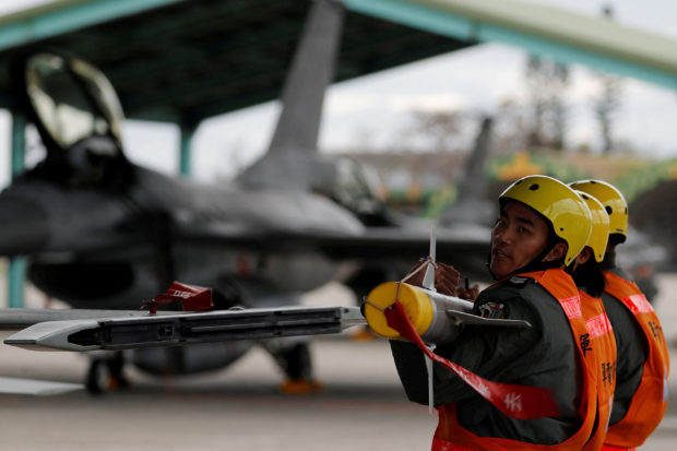 Air force crews lift an AIM-9 Sidewinder air-to-air missiles to be loaded onto Northrop F-5 fighter during a military drill at Zhi-Hang Air Base in Taitung, Taiwan January 30, 2018. REUTERS/Tyrone Siu/File Photo