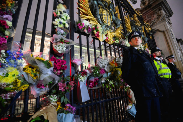Police officers stand guard as flowers are laid at a gate of Buckingham Palace after Queen Elizabeth, Britain's longest-reigning monarch and the nation's figurehead for seven decades, died aged 96, in London, Britain September 8, 2022. REUTERS/Toby Melville