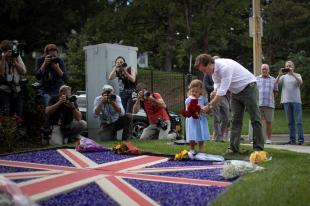 Edward Rodgers helps his daughter, India, lay flowers following the announcement of the death of Queen Elizabeth, at the British Embassy in Washington, U.S., September 8, 2022. REUTERS/Tom Brenner