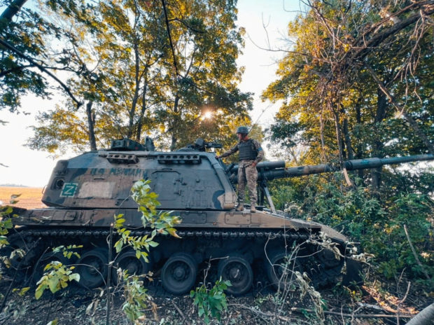 A Ukrainian service member stands on a Russian 2S19 Msta-S self-propelled howitzer captured during a counteroffensive operation, amid Russia's attack on Ukraine, in Kharkiv region, Ukraine, in this handout picture released September 12, 2022. Press service of the 25th Airborne Brigade of the Armed Forces of Ukraine/Handout via REUTERS