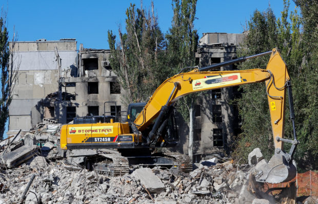 A worker operates an excavator while removing debris of an apartment block destroyed in the course of Russia-Ukraine conflict in Mariupol, Ukraine September 25, 2022. REUTERS/Alexander Ermochenko