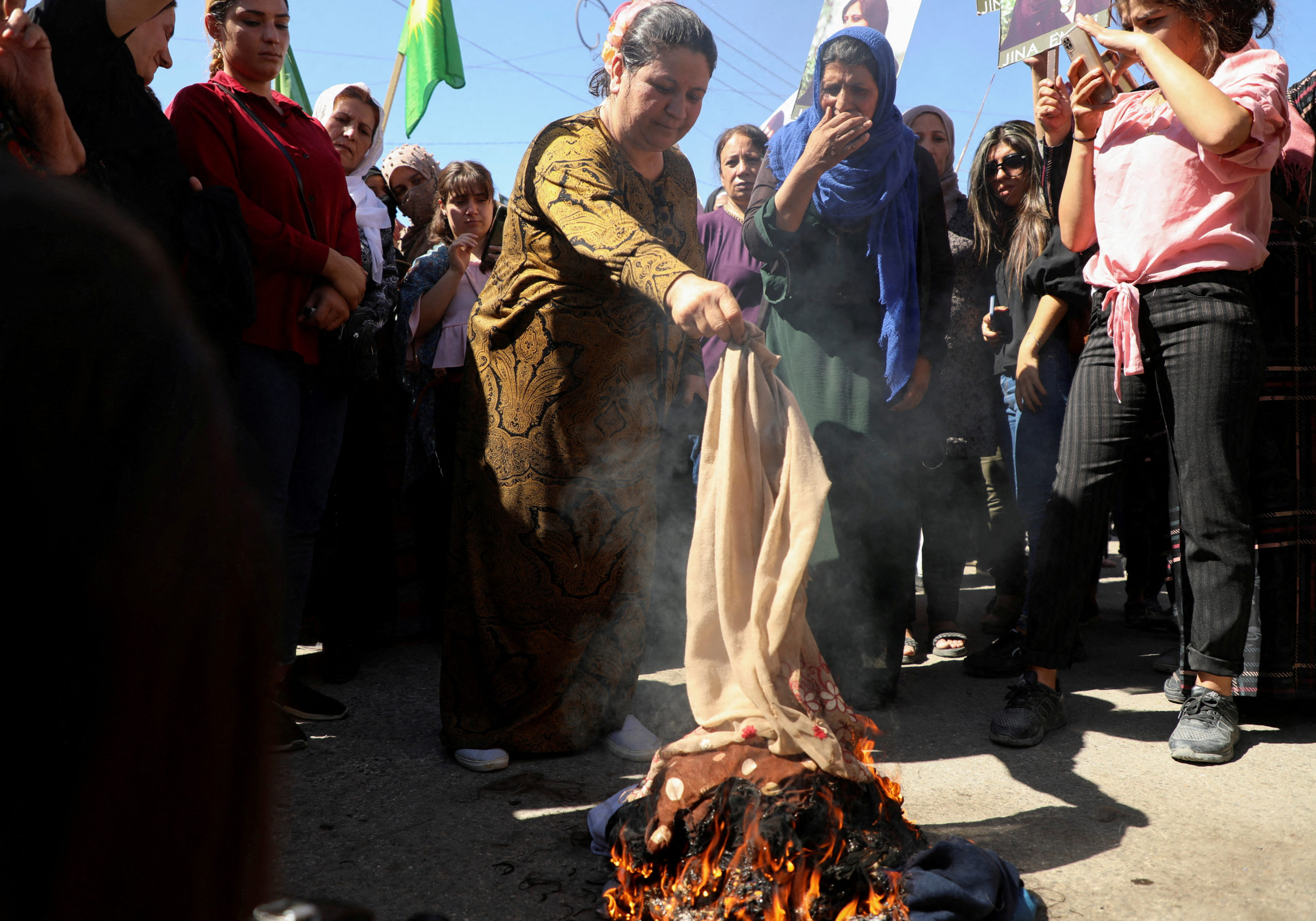 Women burn headscarves during a protest over the death of 22-year-old Kurdish woman Mahsa Amini in Iran, in the Kurdish-controlled city of Qamishli, northeastern Syria September 26, 2022.  REUTERS/Orhan Qereman/File Photo