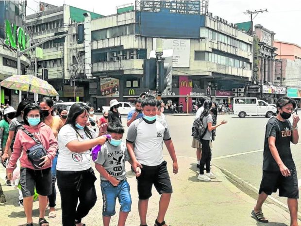 STILL ON Pedestrians crossing a street in downtown Cebu City on Monday still wear face masks despite an order from Mayor Michael Rama relaxing the mask mandate in the city. —NESTLE SEMILLA. STORY: Cebu City sets ‘trial period’ for optional mask use outdoors