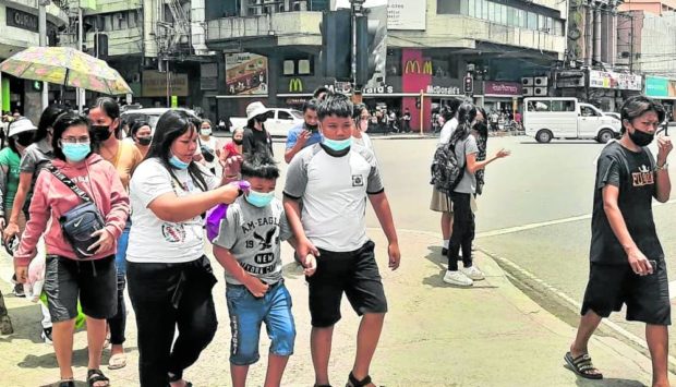 STILL ON Pedestrians crossing a street in downtown Cebu City on Monday still wear face masks despite an order from Mayor Michael Rama relaxing the mask mandate in the city. —NESTLE SEMILLA