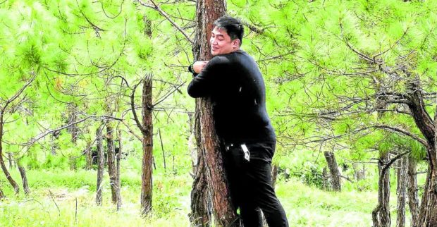 TREE HUGGER   The Baguio government has begun the process of regenerating and expanding its pine tree population, which includes this forest patch at the Baguio Dairy Farm, a favorite hiking site for locals, such as this resident in this photo taken in October 2021. —EV ESPIRITU