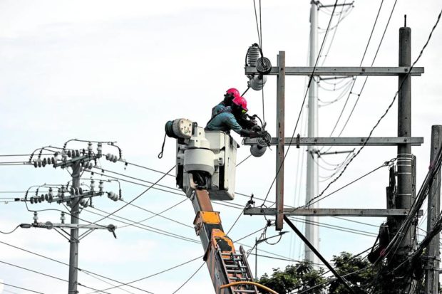 TOUGH JOB Linemen from Manila Electric Co., or Meralco, repair an electric post in a neighborhood in Valenzuela City on Monday. Several areas in Luzon have been experiencing rotating brownouts since Sunday amid the low electricity supply coming from the island’s power plants. —GRIG C. MONTEGRANDE