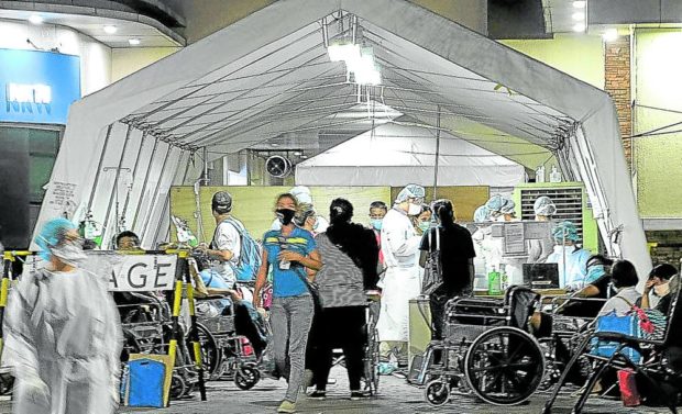 Health workers at the National Kidney and Transplant Institute (NKTI) in Quezon City tend to patients at the triage tent coming in at the hospital Monday evening, March 30, 2020. STORY: Health workers appeal to gov’t for wage increase