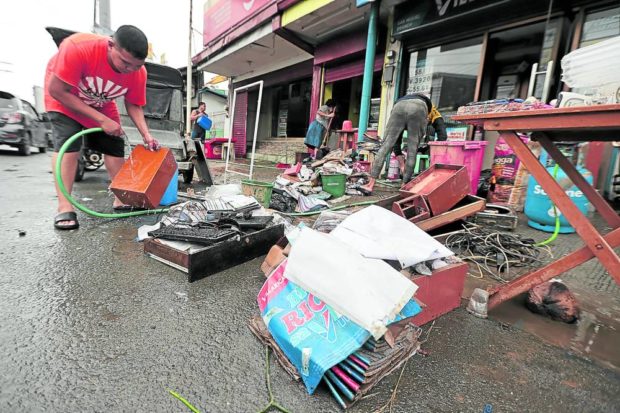 CLEANUP TIME Employees of a flood-hit establishment in San Miguel, Bulacan, start cleaning up their wares and belongings as the skies started clearing up on Monday. —GRIG C. MONTEGRANDE
