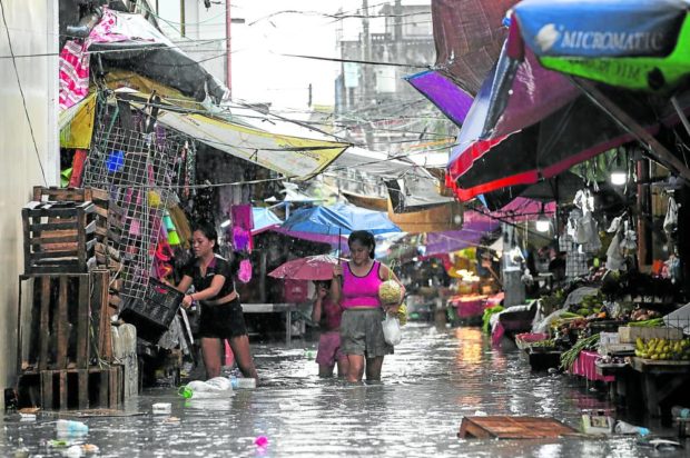 HIGH WATERS, HIGH PRICES Market-goers wade through the flooded old public market in Barangay Dolores in Taytay, Rizal, following a heavy downpour. —LYN RILLON
