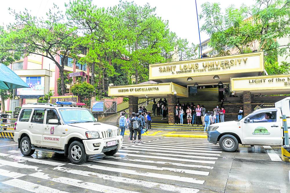 A patrol car passes by the main gate of Saint Louis University in Baguio City on Thursday as the police intensify its security monitoring in local schools
