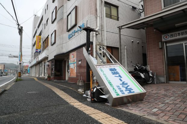 A signboard believed to have been damaged due to strong winds rests over a toppled scooter in Fukuoka on Kyushu island on September 19, 2022, as Typhoon Nanmadol made landfall in southwestern Japan the day before. - Authorities on September 18 urged millions of people to take shelter from the powerful storm's high winds, packing gusts of up to 234 kilometres (146 miles) per hour, and torrential rain. (Photo by JIJI Press / AFP) / Japan OUT