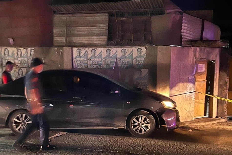 A policeman approaches the car of lawyer Karen Quiñanola-Gonzales where she and her son were shot and wounded by still unidentified suspects