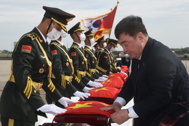 Chinese Ambassador to South Korea Xing Haiming (R) covers caskets containing the remains of Chinese soldiers with a Chinese national flag during the handing over ceremony at the Incheon International Airport in Incheon on September 16, 2022. (Photo by SONG Kyung-Seok / various sources / AFP)