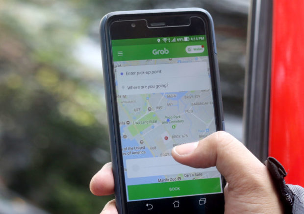 A commuter books a vehicle via ride-hailing app Grab in Manila. STORY: LTFRB okays additional 100,000 Grab vehicles