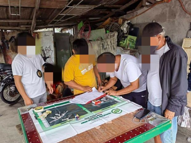 Undercover PDEA and policemen inspect the suspected "shabu" (crystal meth) and other pieces of evidence confiscated from the suspects