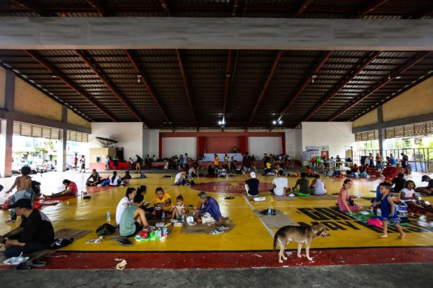 Stranded passengers take a rest inside a gymnasium in Matnog town, Sorsogon province, south of manila on October 28, 2022, after authorities halted ferry service between Matnog Luzon island and Allen in Samar island, ahead of the landfall of Tropical Storm Nalgae. - Landslides and flooding killed at least 31 people as heavy rain from an approaching storm lashed the southern Philippines, with some residents stranded on rooftops, a disaster official said on October 28. (Photo by Charism SAYAT / AFP)