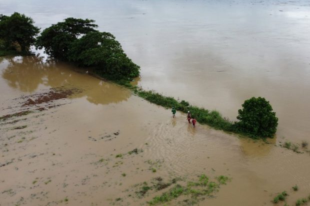An aerial shot shows residents wading through a flooded rice field at a village in Tuguegarao, Cagayan province, north of Manila on October 30, 2022, a day after Tropical Storm Nalgae hit. - Emergency workers scrambled to rescue residents trapped by floods in and around the Philippine capital on October 30 as Tropical Storm Nalgae swept out of the country after killing at least 48 people. (Photo by AFP)