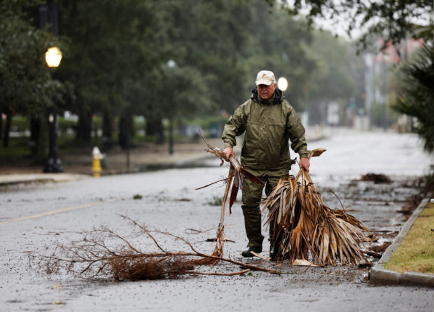 A local resident hauls debris from the road in an effort to keep gutter drains clear as hurricane Ian bears down on Charleston, South Carolina, U.S., September 30, 2022.  REUTERS/Jonathan Drake