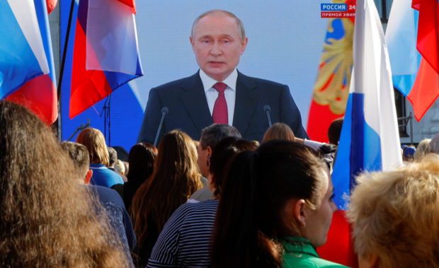 People gather near a screen showing Russian President Vladimir Putin during the broadcast of a ceremony to declare the annexation of the Russian-controlled territories of four Ukraine's Donetsk, Luhansk, Kherson and Zaporizhzhia regions, after holding what Russian authorities called referendums in the occupied areas of Ukraine that were condemned by Kyiv and governments worldwide, in Luhansk, Russian-controlled Ukraine, September 30, 2022. REUTERS/Alexander Ermochenko