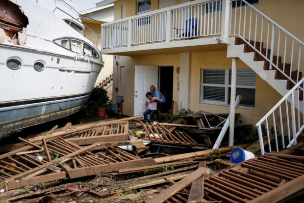 A man helps a woman next to a damaged boat amid a downtown condominium after Hurricane Ian caused widespread destruction, in Fort Myers, Florida, U.S., September 29, 2022. REUTERS/Marco Bello