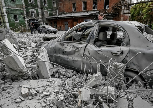 A woman stands near her destroyed car near an old mill, built around 1885, also destroyed during a Russian missile attack in Zaporizhzhia, Ukraine October 14, 2022. REUTERS/Stringer