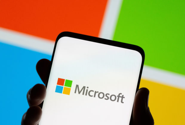 Smartphone is seen in front of Microsoft logo displayed in this illustration taken, July 26, 2021. REUTERS/Dado Ruvic/Illustration