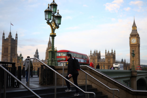 A man walks near the Houses of Parliament during sunrise in London, Britain October 21, 2022. REUTERS/Henry Nicholls
