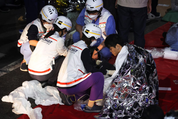 A man receives medical help from rescue team members at the scene where dozens of people were injured in a stampede during a Halloween festival in Seoul, South Korea, October 29, 2022. REUTERS/Kim Hong-ji