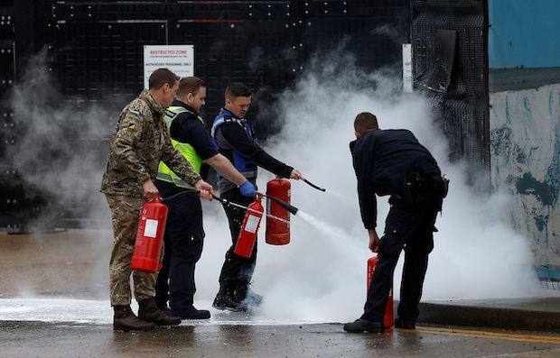 Members of the military and UK Border Force extinguish a fire from a petrol bomb, targeting the Border Force centre in Dover. STORY: Man attacks UK migrant processing center, kills himself