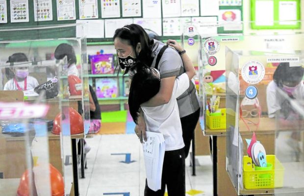 PSYCHIC REWARDS A kindergarten teacher gets a hug from one of her pupils as their reunion marks the resumption of in-person classes at Aurora Quezon Elementary School in San Andres, Manila, in this photo taken on Feb. 9. The school was one of the campuses to lead the return to normalcy after the pandemic lockdowns. —RICHARD A. REYES