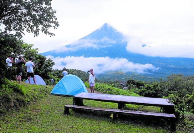 Motorcycle riders take photos of Mayon Volcano at a campsite in Ligao City, Albay. STORY: Mayon activity subsides but Alert Level 2 remains