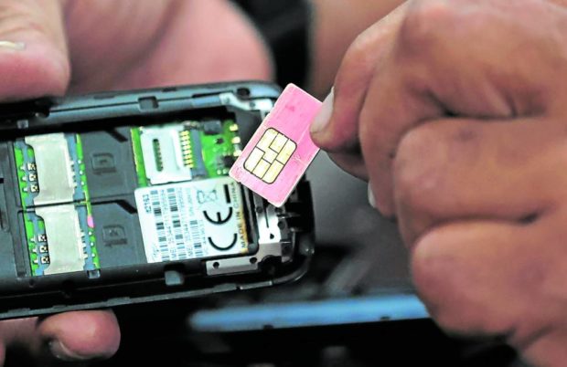 Closeup of man holding SIM card over opened smartphone. STORY: PNP: ‘More teeth’ vs online crime with SIM card law