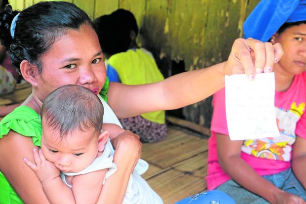 Crisana Lambay, a resident of remote Bati-an village in Maitum, Sarangani, shows off the handwritten note of local government midwife John Mark Odani for her request to have an Implanon insertion, a birth control method. STORY: For T’boli mothers, ‘paltera’ now belongs to the past