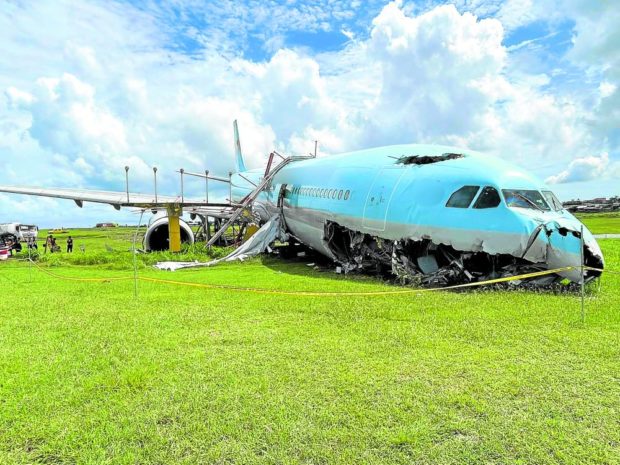 STUCK The Korean Air plane that overshot the runway of Mactan Cebu International Airport on Sunday night remains stuck on a grassy area on Tuesday as airport authorities prepare to transfer the aircraft to another section of the facility. STORY: Night flights halted at Cebu airport after runway mishap