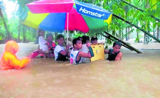 Philippine Coast Guard (PCG) rescuers and residents use a broken refrigerator as a makeshift boat during a rescue operation following flooding due to Tropical Storm Paeng in Hilongos, Leyte province. STORY:  Tragic Paeng combination: Nonstop rains, deforestation