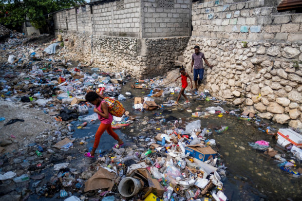 A stream filled with trash runs through a neighborhood in Port-au-Prince
